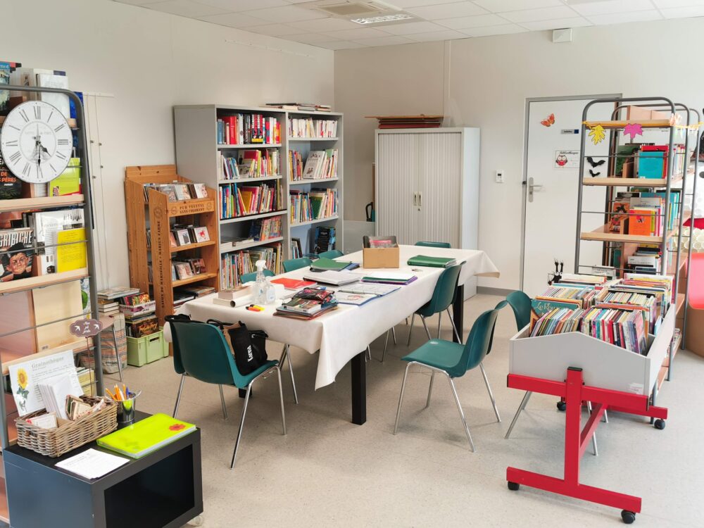 Bibliothèque municipale de Tresserre. La salle et les rayons avec des livres et une table pour lire et travailler.