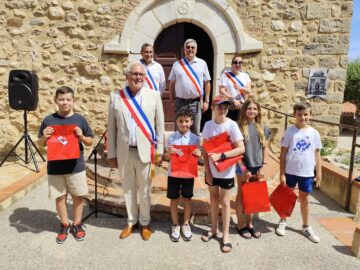 Le Maire de Tresserre, Michel Thiriet, ses adjoints Jean-Baptiste Trilles, Stéphanie Planes et Darren Rigby avec des élèves de CM2 lors de la cérémonie du 14 juillet 2024 au Monument aux Morts, Place Nova à Tresserre